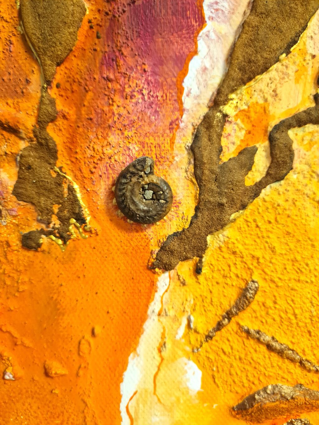 Nahaufnahme einer abstrakten Gemäldeoberfläche mit leuchtenden orangen, gelben und roten Farbtönen sowie einer kleinen, spiralförmigen Struktur in der Bildmitte.
